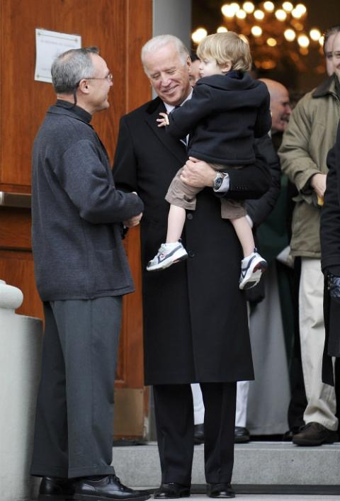 Joe Biden, then vice president-elect, holds his grandson Hunter Biden and shakes hands with Jesuit Fr. Mark Horak following Mass at Holy Trinity Church in Washington Jan. 18, 2009. (CNS/Reuters/Jonathan Ernst)