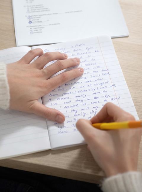 Maria, a refugee from Kyiv, writes about her escape from Ukraine at the United Nations High Commissioner for Refugees reception center in Rzeszów, Poland, Dec. 5. (Marcin Mazur)