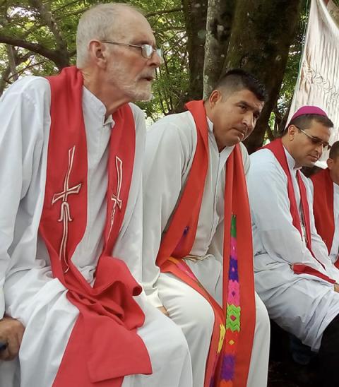 El padre franciscano Brendan Forde, a la izquierda, escucha la Misa el 14 de mayo de 2019 con miembros de la Diócesis de Chalatenango en el lugar de una masacre en un área conocida como Las Aradas en el norte de El Salvador. Forde, un fraile misionero irlandés que vivió algunos de los conflictos más turbulentos de América Latina del siglo XX, murió el 8 de julio de 2023 en Irlanda. (Foto de NCR/Cortesía de la Diócesis de Chalatenango/Roberto Rivas)