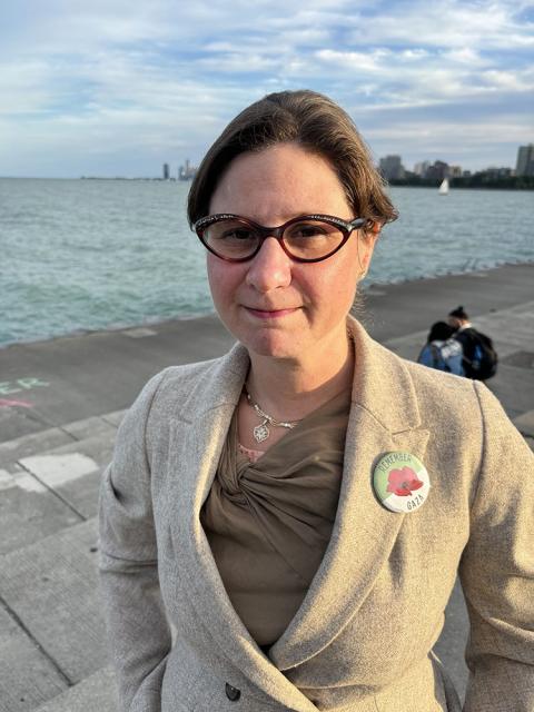 Kaufman stands at edge of lake, wearing a pin reading "Remember Gaza."