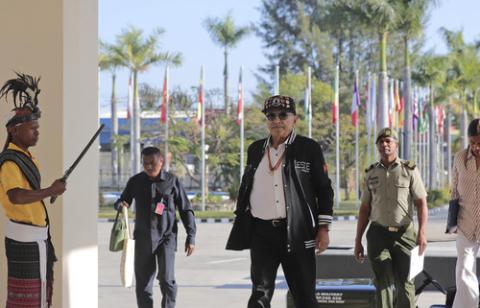 President Ramos-Horta wears casual clothes, waling into palace, palm trees in background.