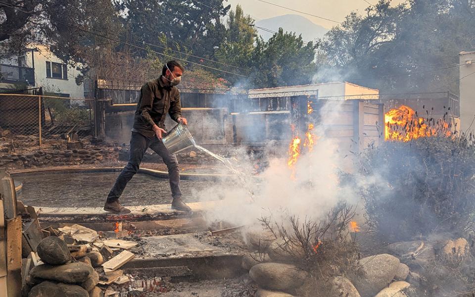 Nick Norman throws a bucket of water on fire in his Altadena neighborhood Jan. 8. He, wife Timithie, brother-in-law Mitchell, and others worked to protect their home and others amid ongoing fires in Altadena and the Los Angeles area. (Courtesy of Nick Norman)