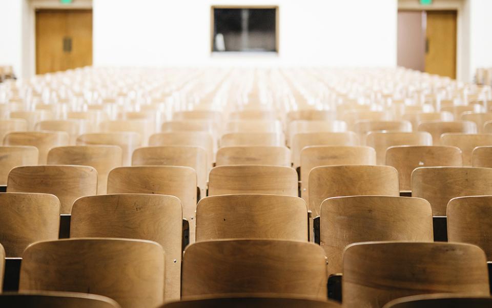 A photo illustration shows rows of seats in an auditorium or a lecture hall setting. (Unsplash/Nathan Dumlao)