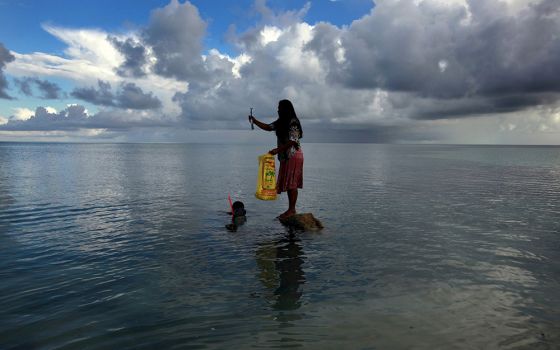 In this May 25, 2013, file photo, a woman holds a fish caught by her husband off South Tarawa in the central Pacific island nation of Kiribati. (CNS/David Gray, Reuters)