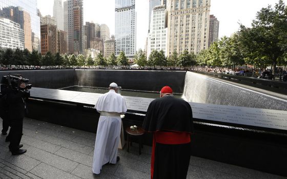 Pope Francis prays at the south fountain at the ground zero 9/11 Memorial Sept. 25, 2015, in New York. The pope is accompanied by Cardinal Timothy Dolan of New York. (CNS/Paul Haring)