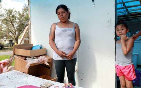 Sandra Guzman is pictured with her daughter, Maria Valentine Romero, in their mobile home Sept. 12. The home had a tarp instead of a roof after the passing of Hurricane Irma in Immokalee, Fla. (CNS/Reuters/Stephen Yang)