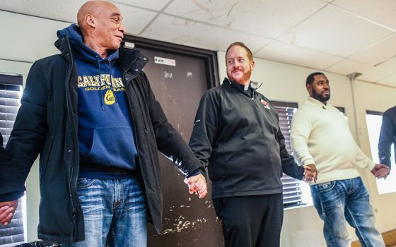 Fr. Matt O'Donnell, pastor of St. Columbanus Parish in Chicago, prays with volunteers before they open the church's Wednesday food pantry in a file photo. In 2020, the church received an estimated $70,000 in Paycheck Protection Program loans. (CNS)