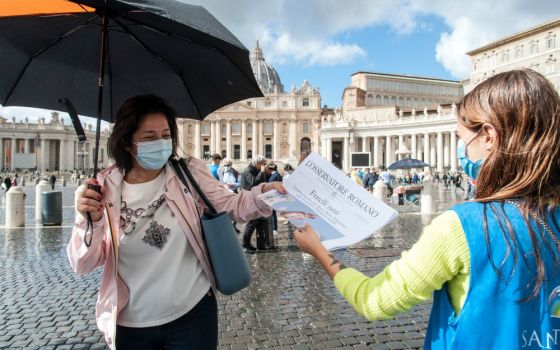 Free copies of the Vatican newspaper L'Osservatore Romano with the front page about Pope Francis' encyclical "Fratelli Tutti" are distributed by volunteers at the end of the Angelus in St. Peter's Square at the Vatican Oct. 4. (CNS/IPA/Reuters/Sipa USA)