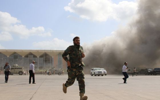 A security member runs during an attack on the airport in Aden, Yemen, Dec. 30, 2020, moments after a plane landed carrying a newly formed Cabinet for government-held parts of the country. (CNS/Fawaz Salman, Reuters)