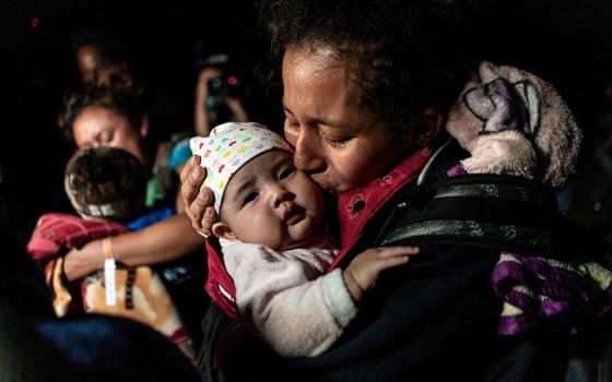 A mother from Guatemala seeking asylum in the U.S. kisses her 3-month-old baby while waiting to be escorted by Border Patrol agents April 7 in Roma, Texas, after crossing the Rio Grande into the United States. (CNS/Reuters/Go Nakamura)