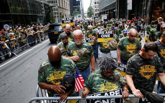 Members of United Mine Workers of America and other labor leaders bow in prayer while picketing July 28, 2021, outside BlackRock's headquarters in New York City as part of the union's strike at Warrior Met Coal Mine. (CNS/Reuters/Brendan McDermid)