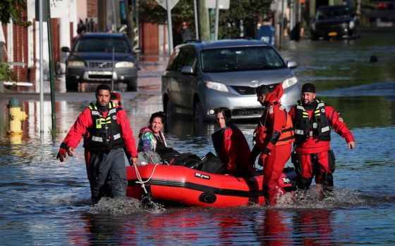 First responders in Mamaroneck, New York, pull local residents in a boat Sept. 2, as they rescue people trapped by floodwaters after the remnants of Tropical Storm Ida swept through the area. (CNS photo/Mike Segar, Reuters)