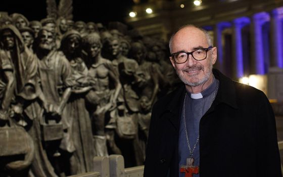 Canadian Cardinal Michael Czerny, undersecretary for migrants and refugees at the Vatican Dicastery for Promoting Integral Human Development, poses for a photo at the "Angels Unawares" statue in St. Peter's Square at the Vatican Dec. 15, 2020. (CNS)