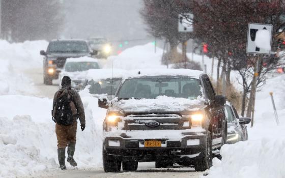 A man walks on the street as cars pass by in Amherst, N.Y., Dec. 26, 2022, during a deadly winter storm that hit the Buffalo region. (CNS/Reuters/Brendan McDermid)