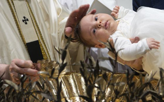 Pope Francis baptizes a baby as he celebrates Mass marking the feast of the Baptism of the Lord in the Sistine Chapel at the Vatican Jan. 9, 2022. (CNS photo/Vatican Media)