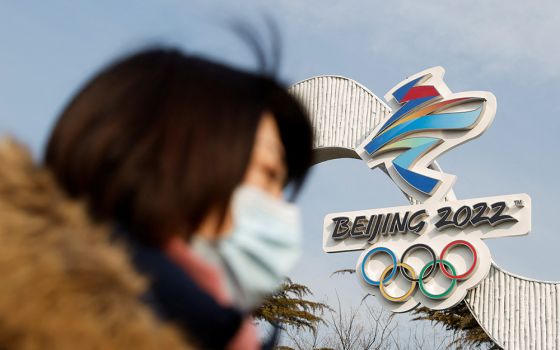 A woman wearing a protective mask walks past the Beijing 2022 Winter Olympic logo Jan. 18. The Olympic & Paralympic Winter Games in Beijing will be held Feb. 4-20 and March 4-13. (CNS/Reuters/Carlos Garcia Rawlins)