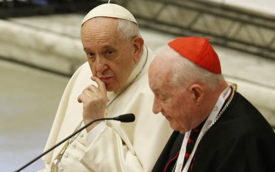 Pope Francis looks on as Cardinal Marc Ouellet, prefect of the Congregation for Bishops, speaks at the start of a symposium on priesthood at the Vatican Feb. 17. (CNS/Paul Haring)