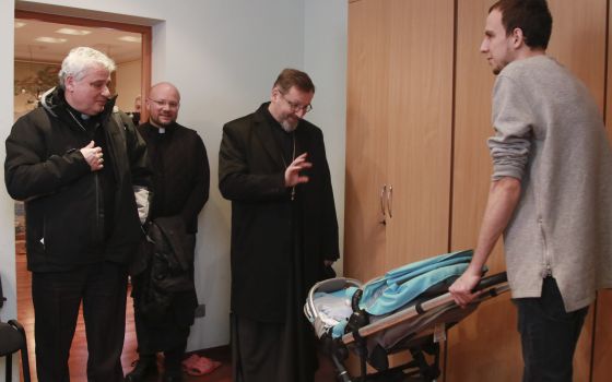 Archbishop Sviatoslav Shevchuk of Kyiv-Halych, head of the Eastern-rite Ukrainian Catholic Church, waves to a child as he and Cardinal Konrad Krajewski, left, the papal almoner, visit with Ukrainian refugees in Lviv, Ukraine, March 10, 2022. (CNS photo/co