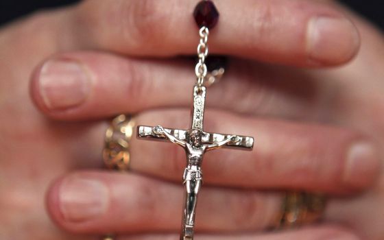 A woman holds rosary during Mass at a church in Armagh, Northern Ireland, March 21, 2010. (CNS photo/Cathal McNaughton, Reuters)