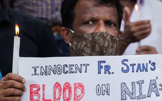 A man holds a candle during a prayer service for Jesuit Father Stan Swamy in Mumbai, India, July 6, 2021, a day after he died at a hospital. (CNS photo/Francis Mascarenhas, Reuters)