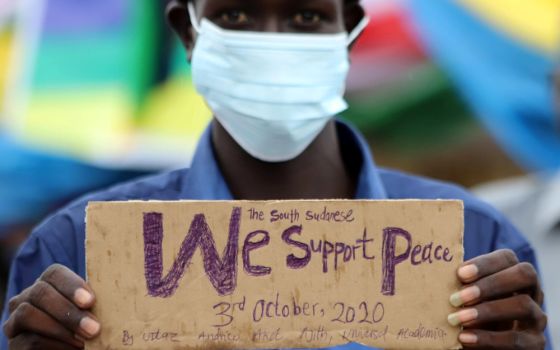 A civilian holds a placard in support of peace as he celebrates the signing of peace agreement between Sudan's transitional government and Sudanese revolutionary movements to end decades-old conflict, in Juba, South Sudan, in this Oct. 3, 2020, file photo