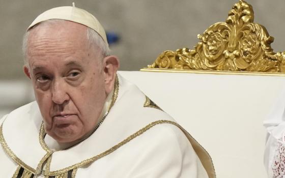 Pope Francis wears white and gold vestments and sits in a white and gold chair