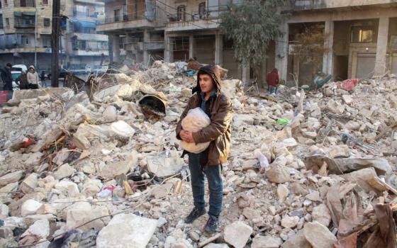 A young person stands on top of and amid concrete rubble