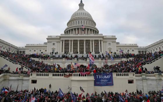 Crowds of people with Trump banners and American flags cover the outside of the Capitol building