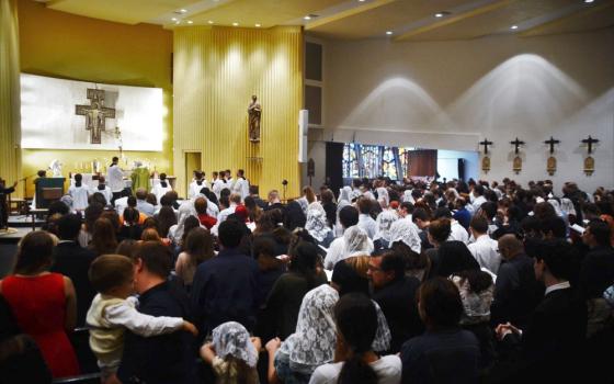 A photo from the back of a group of people gathered for mass. Women have lace headcoverings, and all altar servers are male.