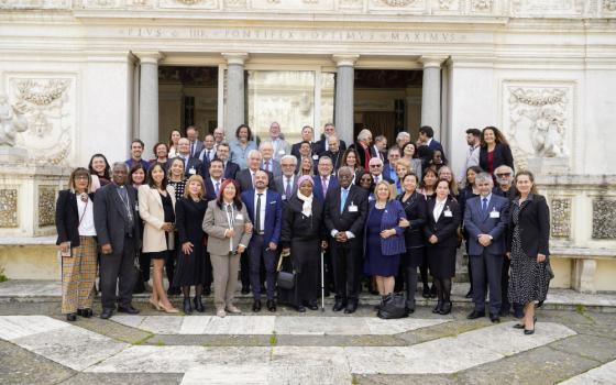 A medium-sized group of people poses for a group photo in front of a marble wall