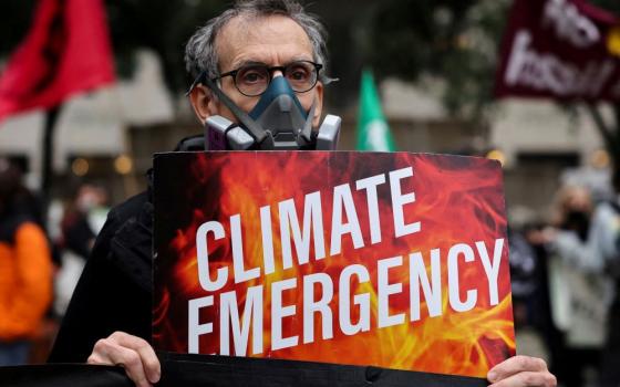 A climate activist wearing a protective mask protests June 8, 2023, while smoke and haze caused by wildfires in Canada pass through New York City. (OSV News photo/Amr Alfiky, Reuters)