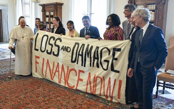 Pope Francis joins others in holding a banner during an audience at the Vatican June 5, 2023, with the organizers of the Green & Blue Festival. The banner calls for financing a "loss and damage" fund that was agreed upon at the COP27 U.N. climate conference in 2022. The fund would seek to provide financial assistance to nations most vulnerable and impacted by the effects of climate change. (CNS photo/Vatican Media)