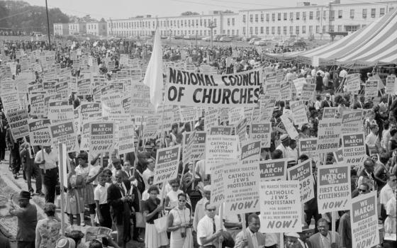 A black and white photo of protesters on the National Mall carrying signs for racial justice