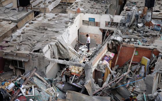 A person stands on the top of rubble from destroyed buildings