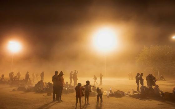 Migrants are battered by dust kicked up by high winds as they wait to be picked up by U.S. Customs and Border Protection officers near the U.S. border wall near El Paso, Texas, May 10.