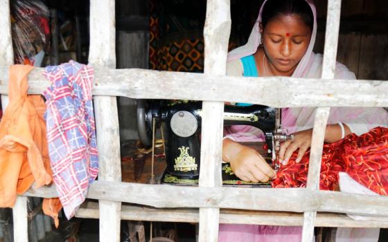 Woman works on a sewing machine in front of a window. 