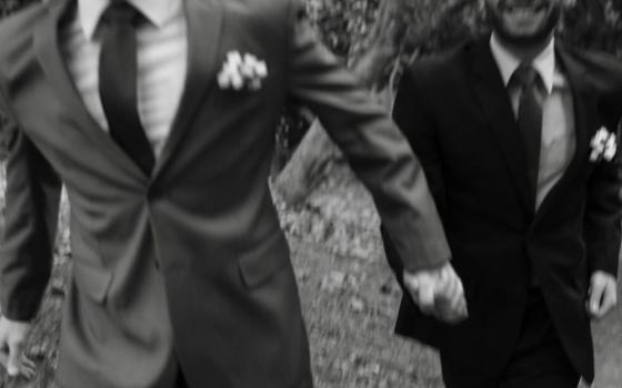 Two men wearing suits and holding hands