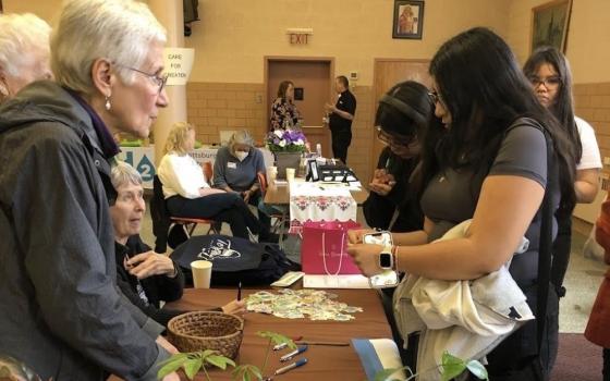 Roberta Zolkoski welcomes visitors to the Earth Day Community Resources Fair at St. Teresa of Kolkata parish, St. Catherine of Siena church, in Pittsburgh. 