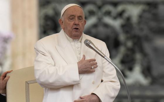 Pope Francis standing with hand to heart and eyes closed