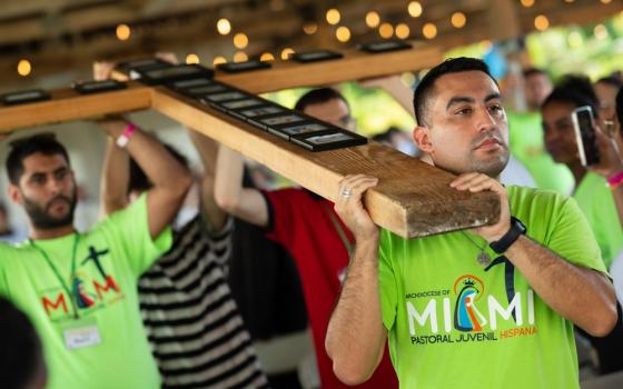 Young people carry large cross in procession. 