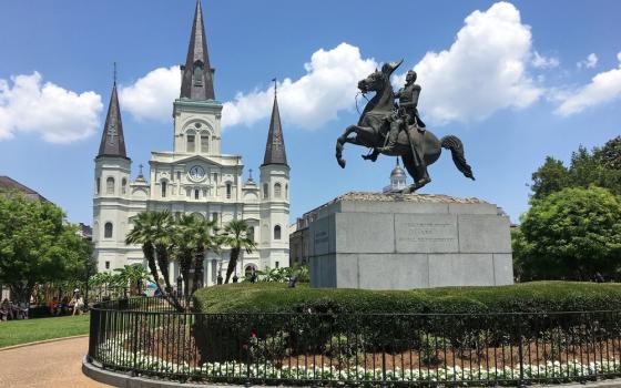 Towering Cathedral and equestrian bronze statue foregrounded against blue sky.