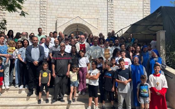 Cardinal, vested, stands on church steps, surrounded by faithful of Gaza.  