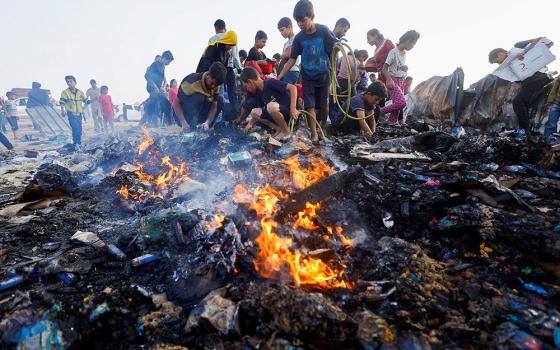 Palestinians search for food among burned debris May 27, 2024, in the aftermath of an Israeli airstrike on an area designated for displaced people in Rafah, in the southern Gaza Strip. (OSV News/Reuters/Mohammed Salem)