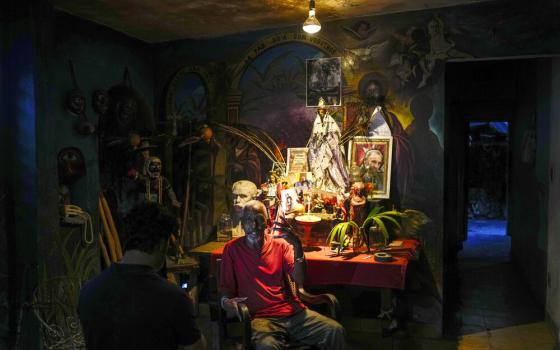 Man sits in front of altar in dim room