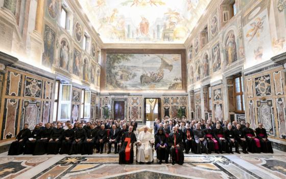 Pope sits flanked by other dignitaries, and backed by large assembly of conference participants. 