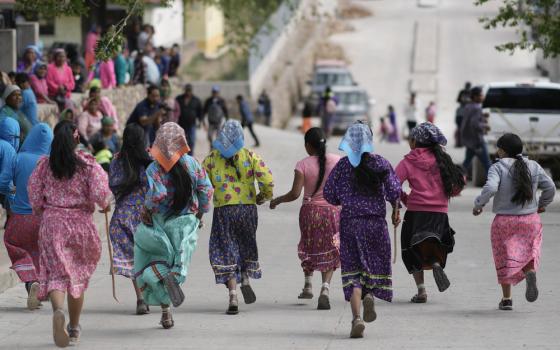 Women wearing brightly colored skirts and headscarves, pictures from behind, running through street.