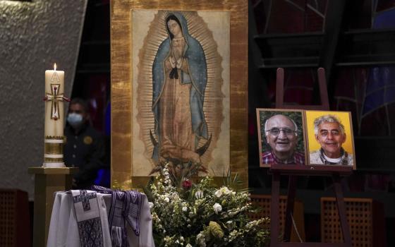Framed photographs rest on altar before image of Our Lady of Guadalupe