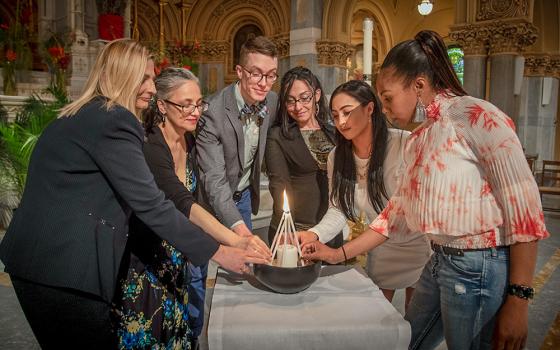 Graduates of Xavier Mission's Life Skills Empowerment Programs, or LSEP, take part in a candle-lighting ceremony at St. Francis Xavier in New York City in May 2018. The ceremony is intended to signify the community of the participants in the program, as individuals joining together in one unit. (John Langdon)