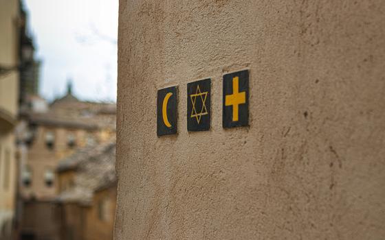 Black and yellow religion symbols are pictured adorning an outside wall. (Unsplash/Noah Holm)