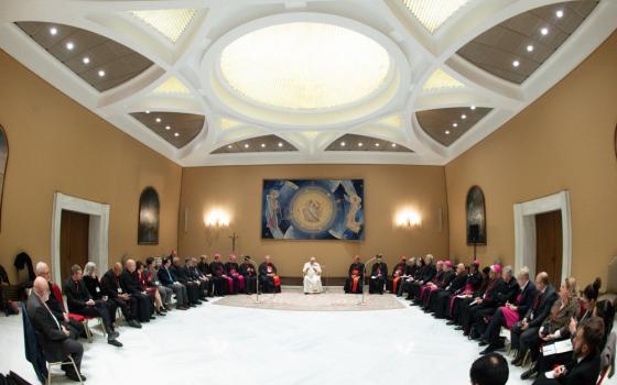 Pope Francis sits in middle of large u-shaped assembly. 